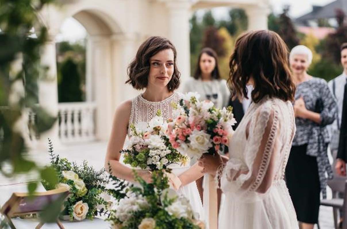 Portrait of two loving female lesbian LGBT brides telling their marriage vows at the wedding ceremony in front of wedding officiant